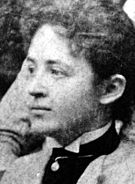 A Caucasian female in profile wearing a high collared shirt with upswept hair.