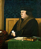 A Tudor man in a large coat and hat, possibly of fur, sitting at a desk.