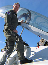 Dan Clark on the wing of a jet fighter in a flight suit.
