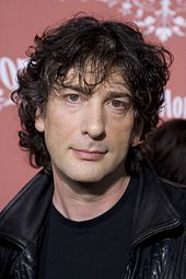 Photograph of man's head. He has black, curly, mussed hair, and a piercing expression.