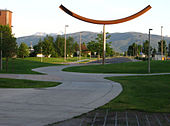 A metal sculpture on a college campus, with mountains in the far distance.