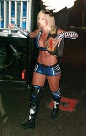 Michelle McCool walking towards the ring with the WWE Women's Championship belt over her shoulder