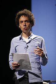A man holds a piece of paper and is giving a speech