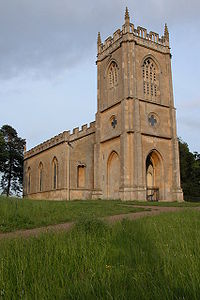 A stone church seen from the northwest, with a tower containing a porch in the foreground, and embattled body of the church stretching behind it