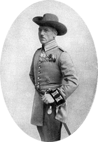 Man in uniform, with bush hat, upswept brim on one side and accouterments such as sword, also wearing medals