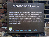 Plaque headed "Marshalsea Prison", saying "Beyond this old wall is the site of the old Marshalsea Prison, closed in 1842. This sign is attached to a remnant of the prison wall. Charles Dickens, whose father had been imprisoned here for debt in 1824, used that experience as the Marshalsea setting for his novel Little Dorrit." "HISTORIC SOUTHWARK" is at bottom.