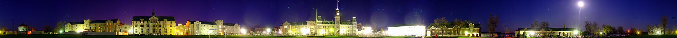 A 260 degree photo of the Royal Military College of Canada in  Kingston, Ontario, on the 4th of May 2007.  Seen is a green landscape during the night, featuring  buildings made of white stone and red brick. The night sky is  dark blue and purple, with the moon shining bright on the right side of the image.  Photo credit: Martin St-Amant (User:S23678)