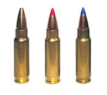 Photo of three 5.7×28mm cartridges as used in the P90. The left cartridge has a plain hollow tip, the center cartridge has a red plastic V-max tip, and the right cartridge has a blue plastic V-max tip.