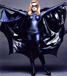Alicia Silverstone poses, arms wide to billow the cape, in the costume used for Batgirl in the film Batman & Robin.