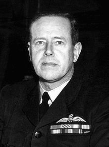 Head-and-shoulders portrait of man in dark military uniform with ribbons and pilot's wings on chest