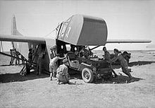 Four men pushing a jeep into a glider via teh raised front cockpit