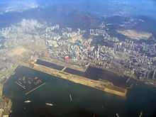 Aerial view of a runway of an airport. It is surrounded by a harbour.