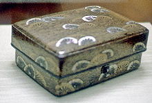 Box with design of wheels in gold and white on black background all over.