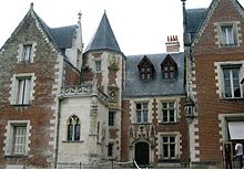 Photo of a large medieval house, built of brick with many windows and gables and a circular tower with a conical roof.