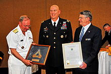 Rear Admiral James (Phil) Wisecup, President of the U.S. Naval War College and Rear Admiral (Ret) Glenn E. Whisler, Jr., Chairman, Naval War College Foundation Board of Trustees, present General Raymond T. Odierno, Commander, Multi-National Force-Iraq and Operation Iraqi Freedom with the Naval War College Distinguished Graduate Leadership Award at the Naval Support Activity Washington - Washington Navy Yard Catering and Conference Center. (U.S. Navy photo by Joseph P Cirone/Released).