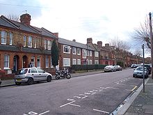 Three houses of an obviously 1950s rectilinear design are surrounded by typical Victorian Gothic houses
