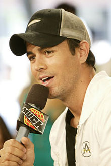 A man wearing a black-and-white baseball cap speaks into a microphone