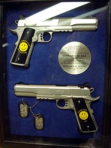 A case with two handguns, both with an stamped Smiley Face - one of the guns has "To Edward Blake, With Gratitude" around the Smiley, while the other has "Richard Nixon - 1976" -, dogtags, and a circular plaque, written by Richard Nixon, stating they are a gift to the Comedian in recognition for his services.