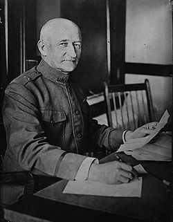 A black and white image of Edwards sitting at a desk working. He is wearing his military uniform and looking directly at the camera.