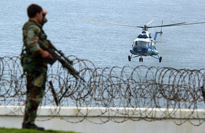 A US Military Special Operations Security Team Member observes a United Nations MI-8 Hip helicopter approaching the US Embassy in Monrovia, Liberia on 13 June 2003