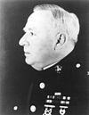 Side profile of head and chest of older, plump man in dress U.S. Marine uniform.