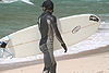 Surfer in wetsuit carries his surboard on the beach.JPG