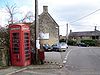 Street scene. Red telephone box and telegraph pole. Stone buildings around road junction.