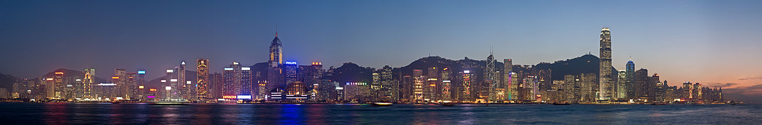 Night time city skyline with Victoria Harbour in front and low hills behind