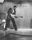 Carl Perkins plays guitar on stage