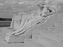A reclined topless female statue that is visibly upset. Her hands fiddle with the sheet that covers her from her waist to her feet.