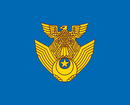 A golden symbol placed on a blue background. The golden symbol is an eagle perched on a pair of wings.