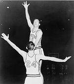 A basketball player, wearing a jersey with a word "PRINCETON" and the number "42", is jumping in front of another basketball player who is wearing a jersey with the number "24".