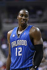 A man, wearing a blue jersey with a word "ORLANDO" and the number "12" written in the front, is standing in front of the crowd.