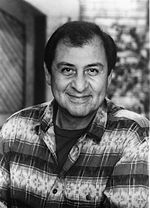 Mexican-American man in his sixties, smiling at viewer and wearing a striped shirt.