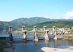 A river dam made of five concrete pylons and metal shutters.
