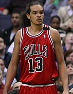 A basketball player, wearing a red jersey with the word "BULLS" and the number 13 on the front, is standing on a basketball court.