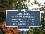 A bronze marker with a map of the State of New York at the top, under which is the word Birthsite and other text