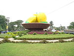 Photo of painted "sculpture" of mango at the center of a road roundabout