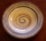 A plate with a spiral pattern in the middle and a stripe pattern along the rim.