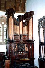 A pipe organ in a church with an elaborately carved wooden case