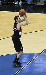 A basketball player, wearing a black jersey shooting a free throw.