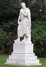 White stone statue of a man in a toga, in a park
