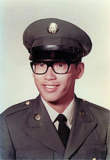 Asian American male wearing Army Dress Green Uniform and glasses posing for a photo.