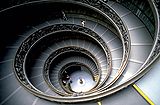 Vast spiral staircase, half in darkness. It is a stepped ramp about 15 meters in diameter, and descends 5 stories at about a 10 degree incline.