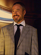 A white man with a thin beard, wearing a suit, and looking to his right, smiling.