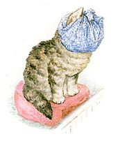 A kitten sitting on a hassock with a dust cloth wrapped over her face and head