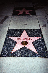 A five pointed pink star inlaid in the sidewalk with Bob Marley written on it.
