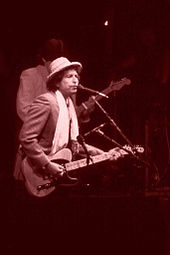Dylan performing onstage with an electric guitar.
