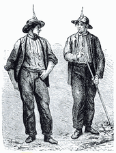 Two men wearing mining attire look at one-another in this black line drawing. Both wear dark clothing and mining helmets. The man on the right holds a long tool.