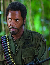 A film screenshot showing the same man wearing extensive makeup to appear as an African American.
